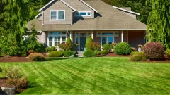 A large tan house with green front yard
