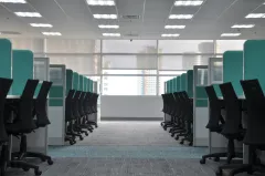 Two rows of cyan cubicles with black chairs at them