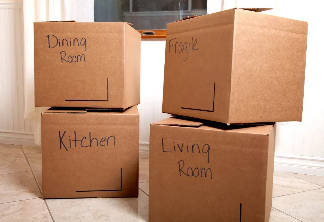 Stacked cardboard boxes with various labels on them for different rooms.