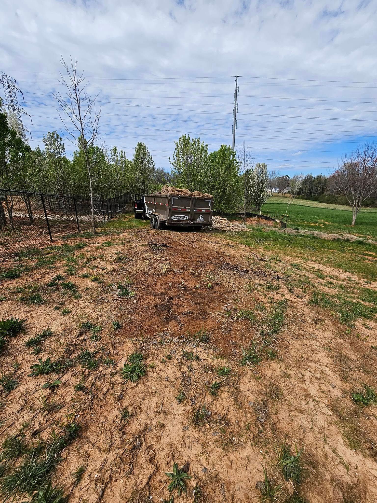 A flatbed trailer filled with harvested fruit in an orchard, under a cloudy sky.