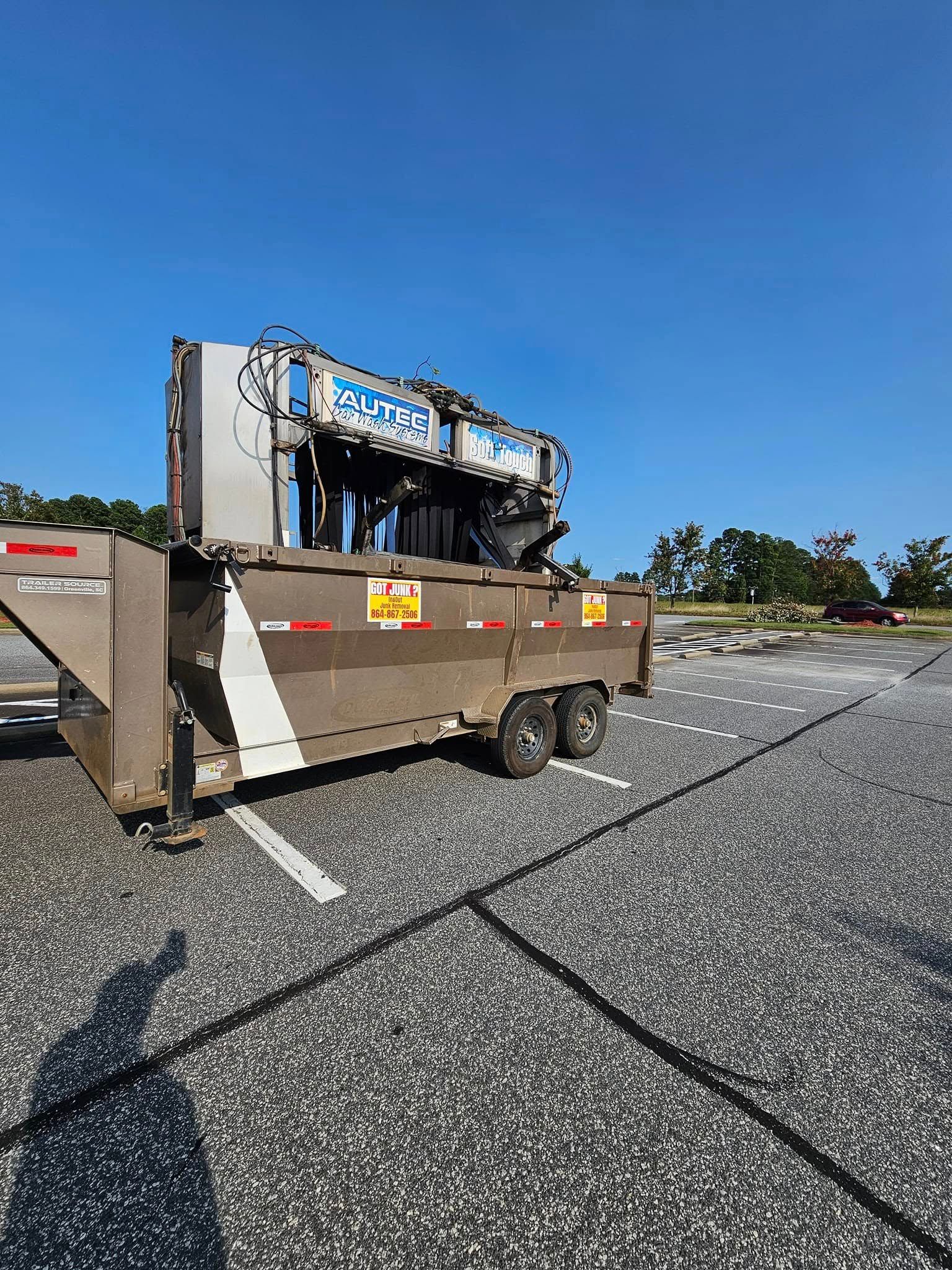 A large trailer with machinery, parked on a gray surface under a blue sky.