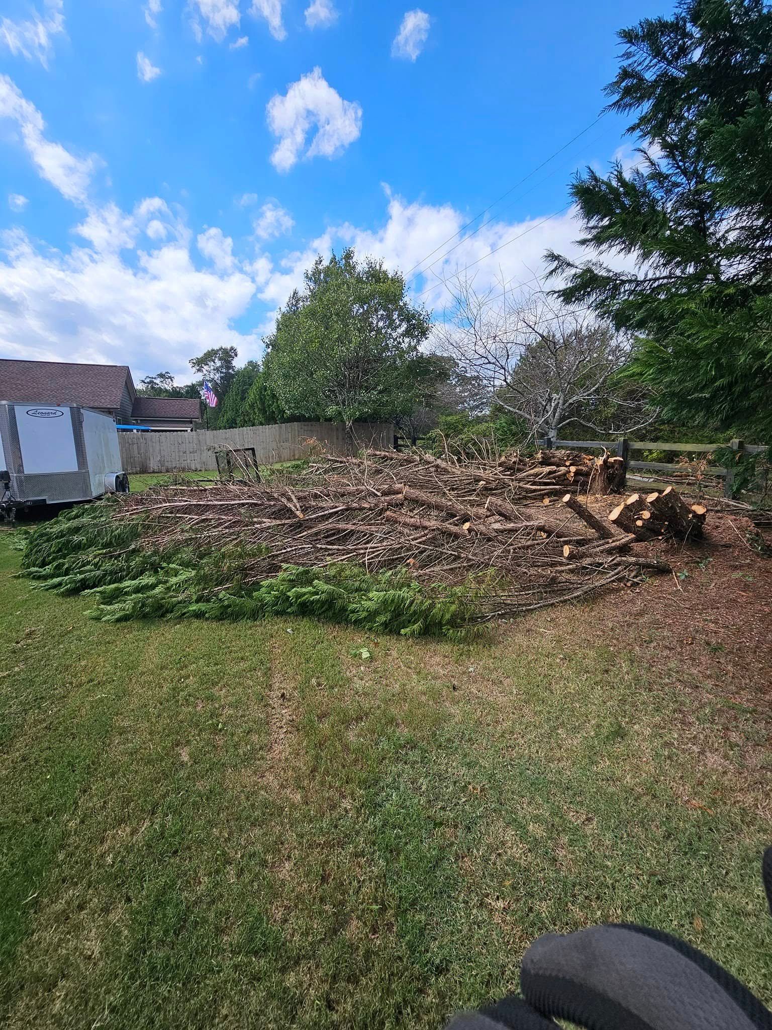 Pile of bricks and debris in a yard with grass, trees, and a partially constructed building against a bright blue sky.