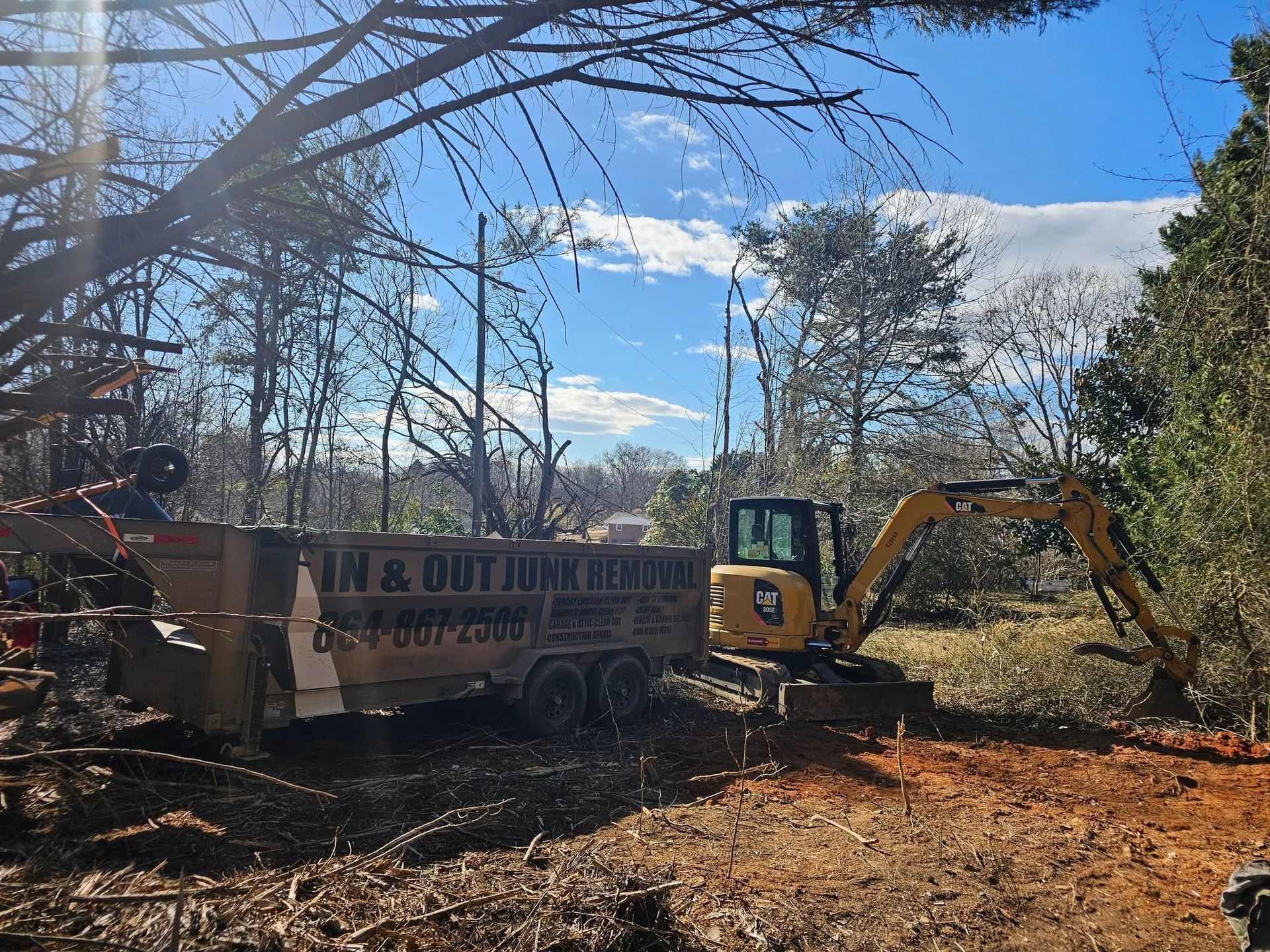 A small yellow excavator loading debris into a 