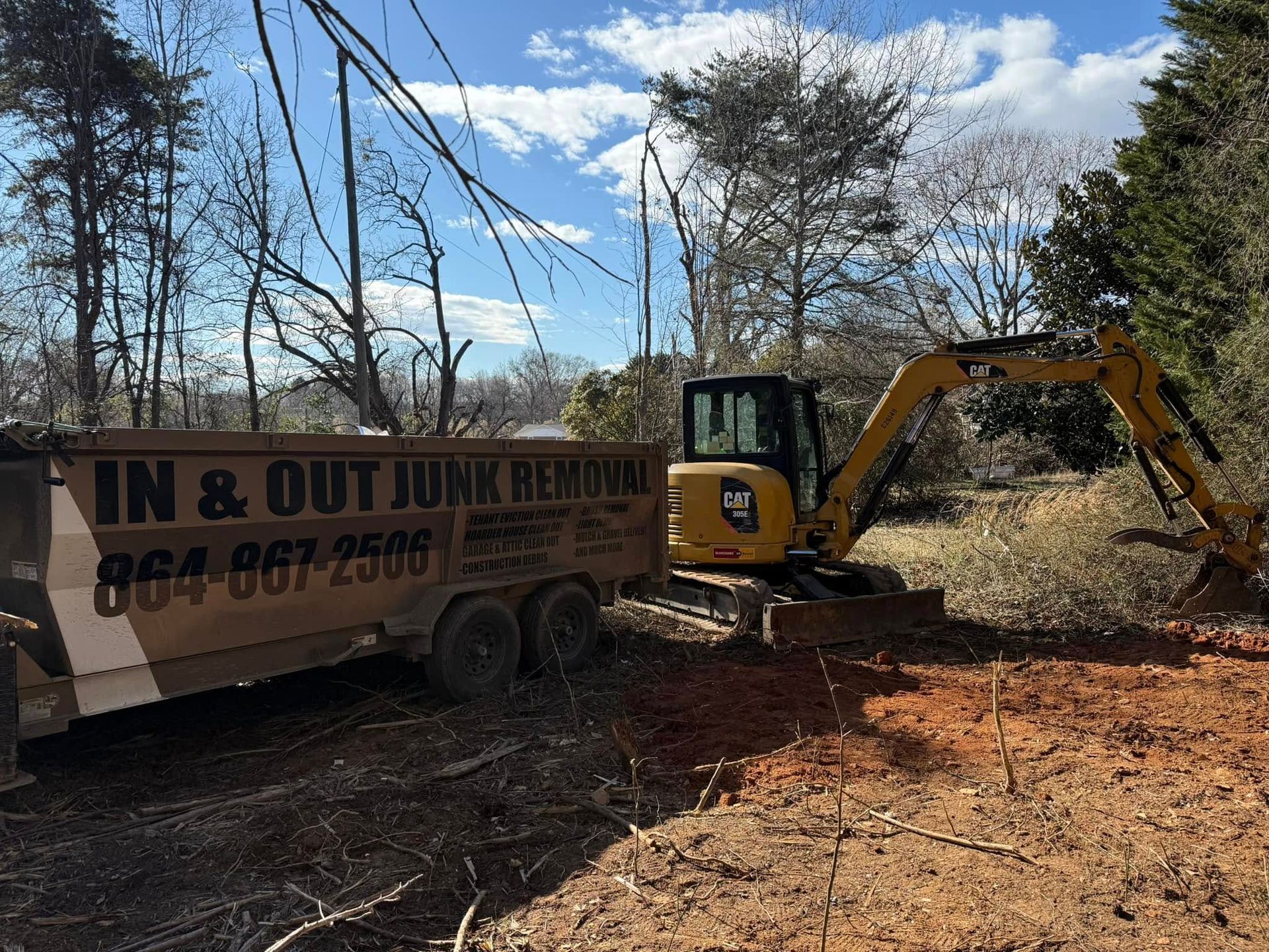 An excavator loading debris into a trailer for In & Out Junk Removal. Outdoors, daytime.