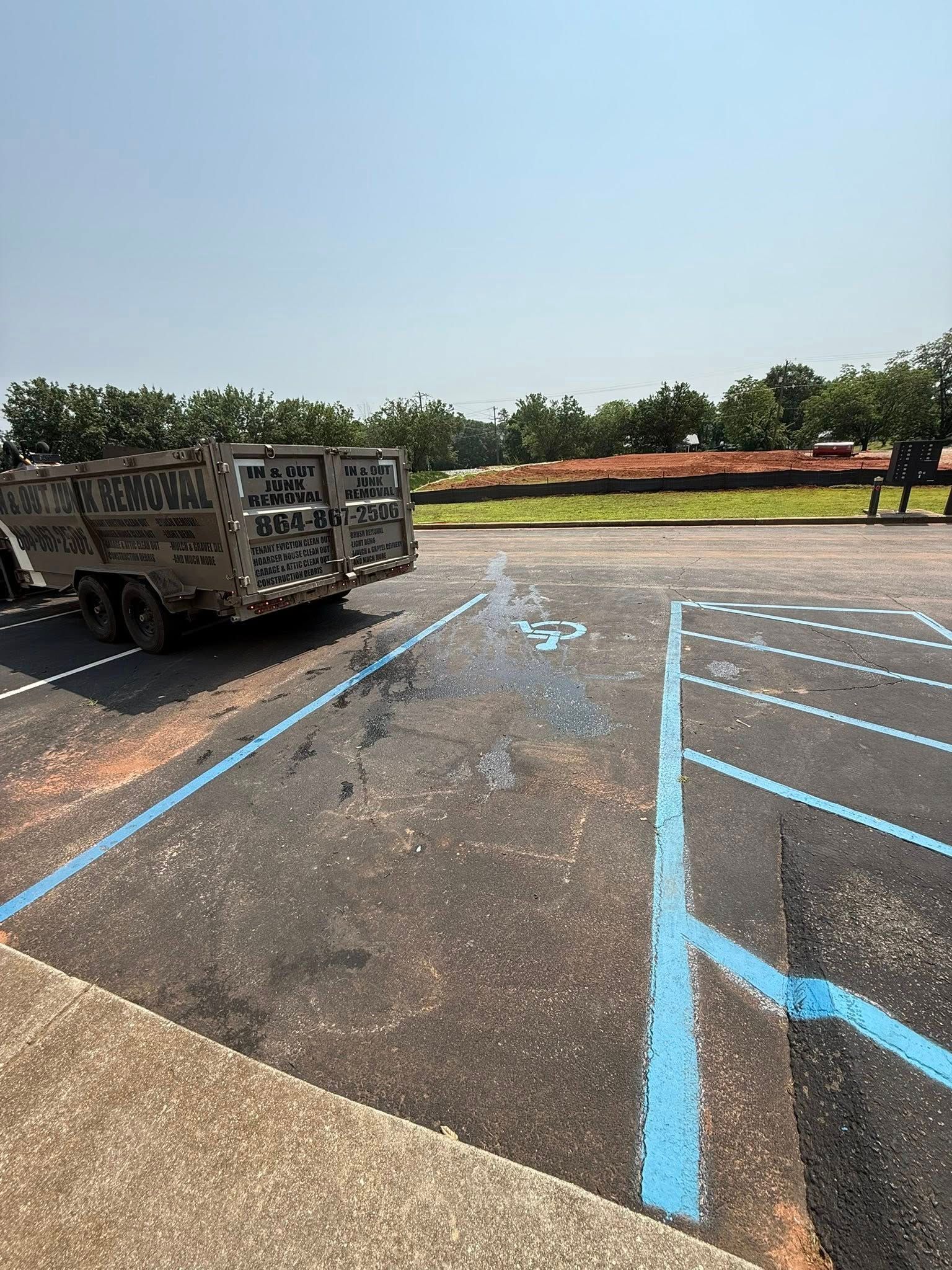 A trailer parked in a newly painted parking space, blue handicap parking symbol, sunny outdoor setting.