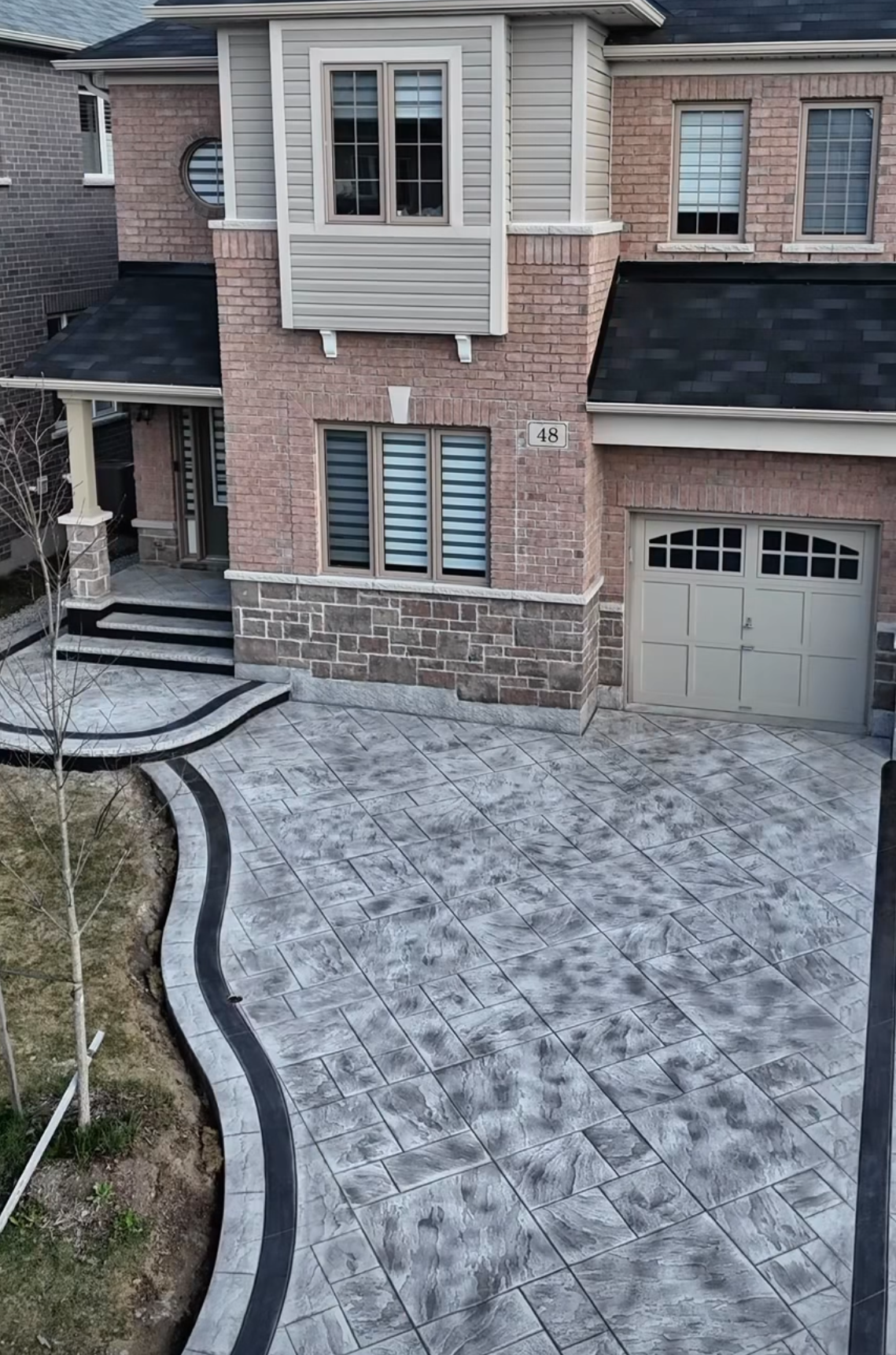 Exterior of horse ranch with french windows, concrete driveway and green bushes around.