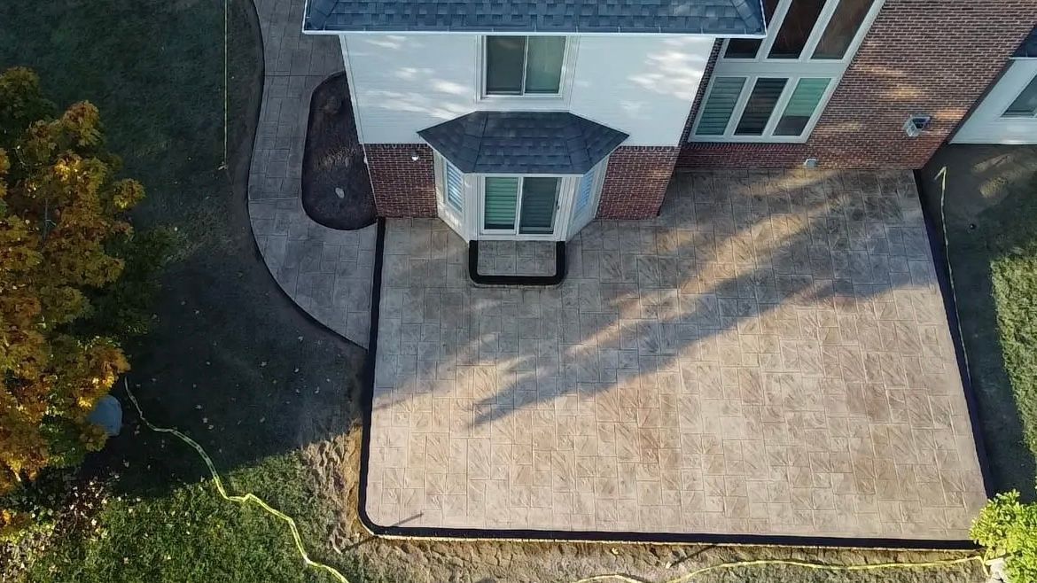 High angle view of a stylish outdoor kitchen, gas barbecue and dining table set for entertaining guests with formal place settings and flowers on a paved patio