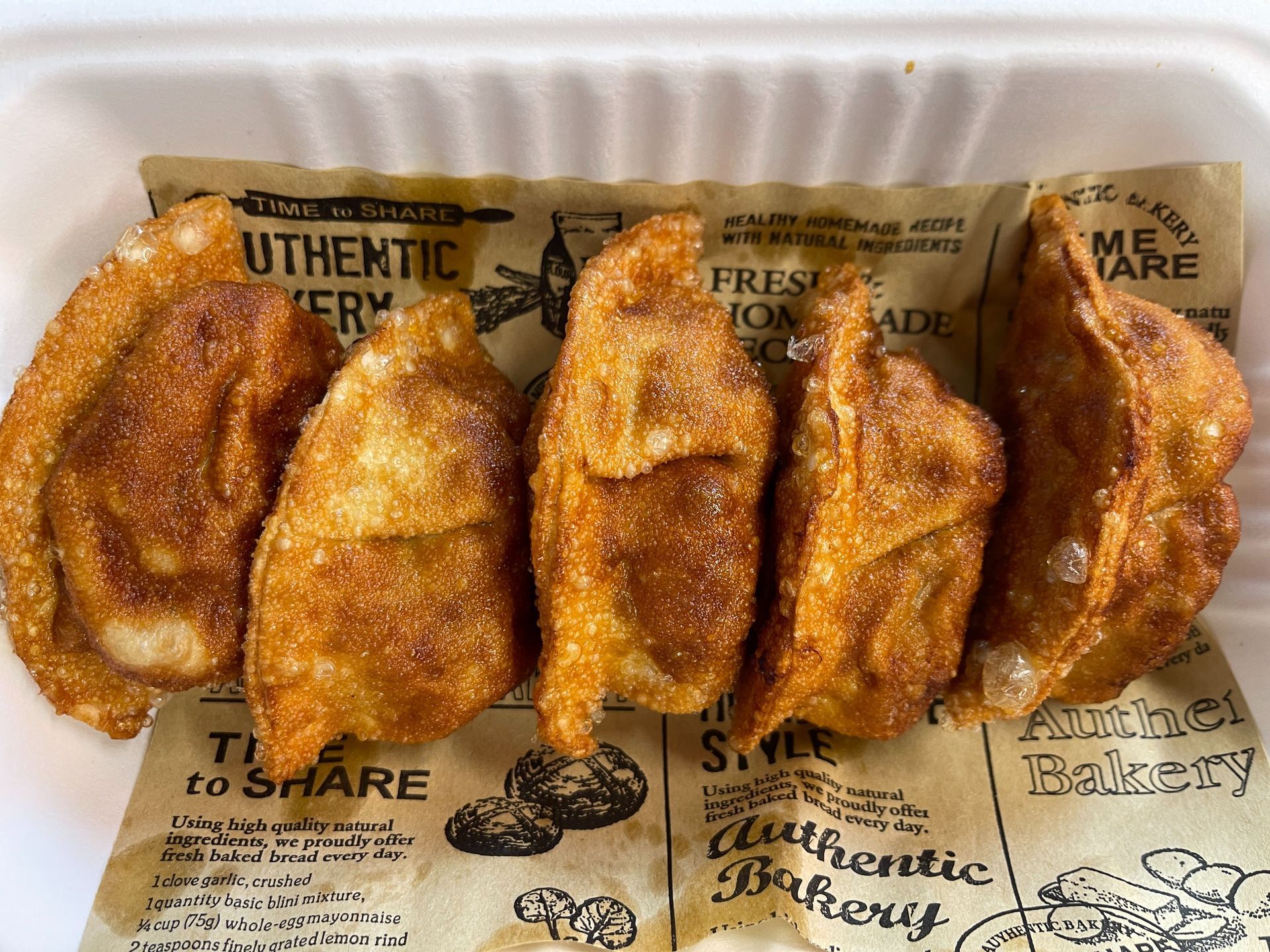 Fried chicken cutlet with rice and salad, drizzled with sauce, on a white plate.