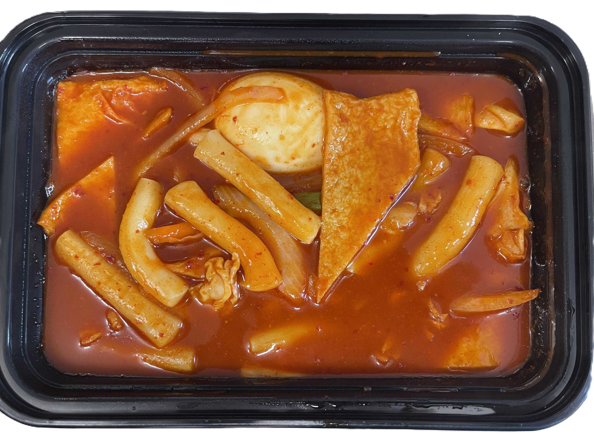 Grilled chicken salad in a metallic tray, featuring lettuce, vegetables, and drizzled sauce, on a white surface.