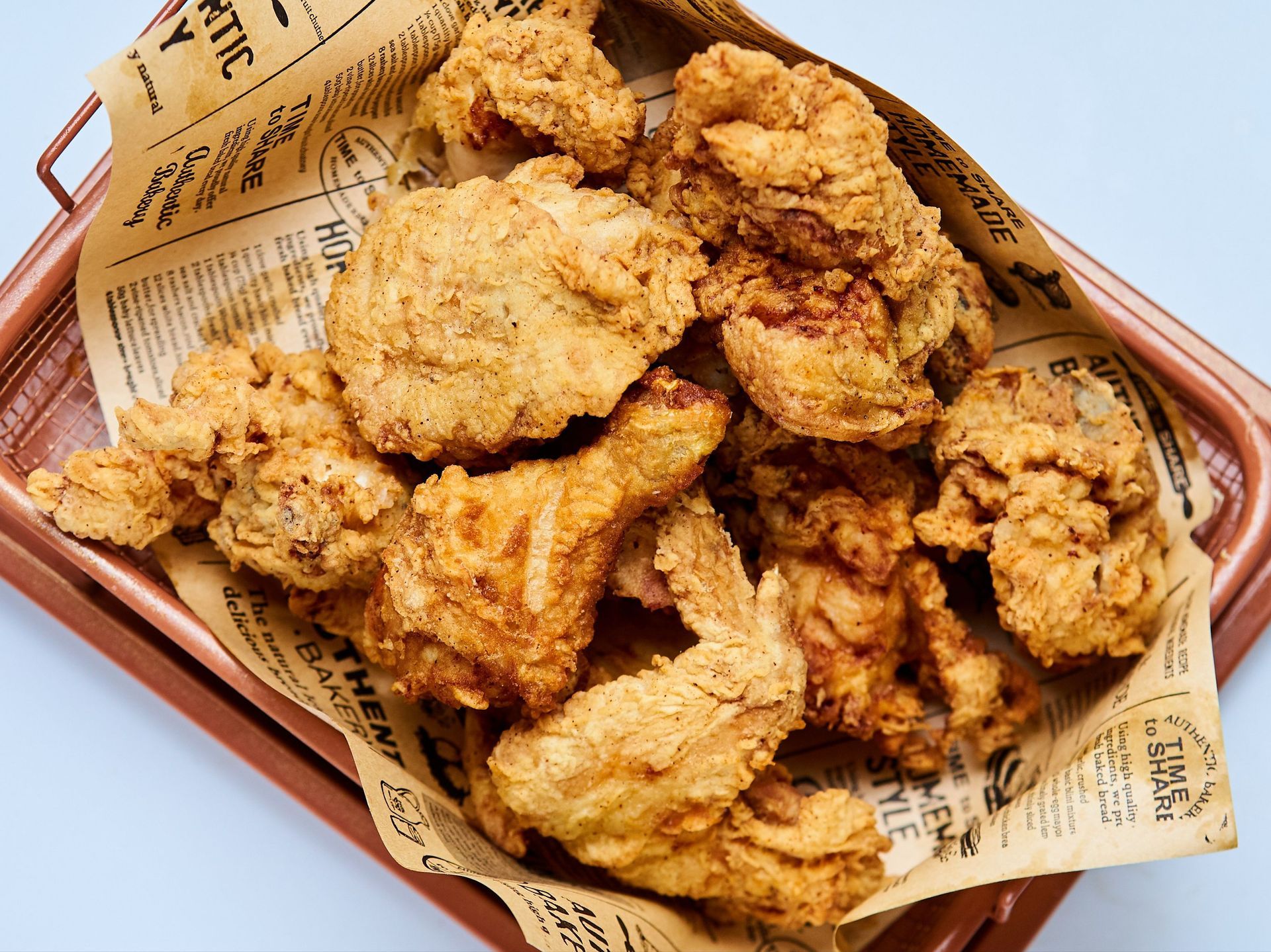 Fried chicken pieces and coleslaw on a decorative paper liner, served on a silver tray against a white background.