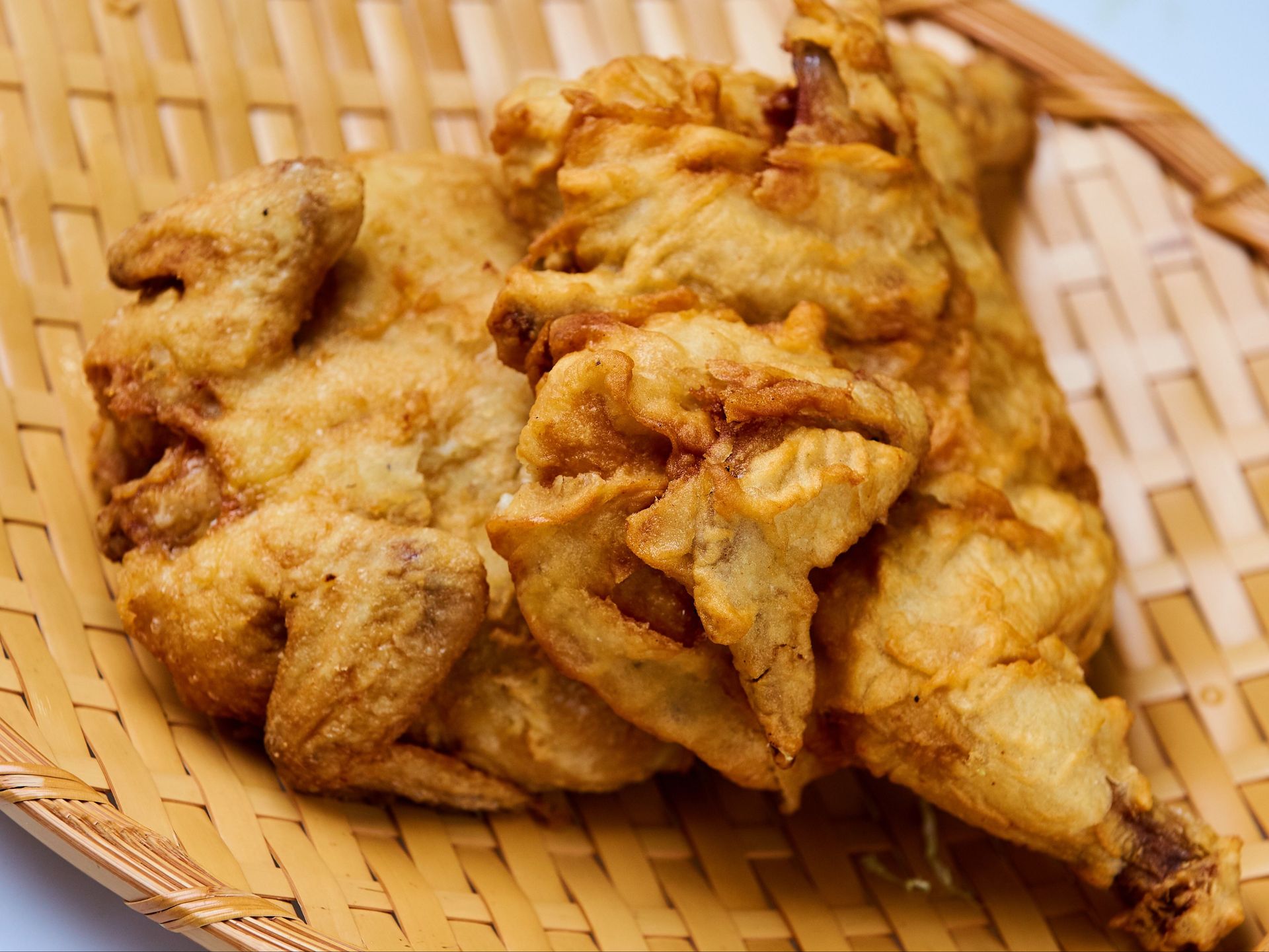 Fried chicken and shredded cabbage on a silver tray lined with patterned paper.