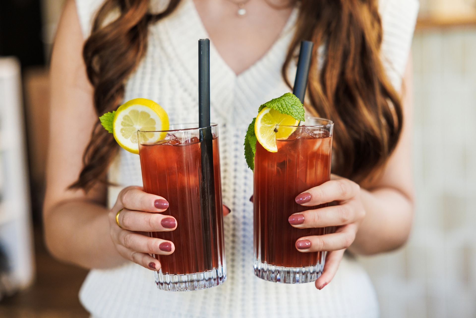 Chicken salad with two drinks on a tray. The salad contains lettuce and greens. One drink is yellow, the other is red.