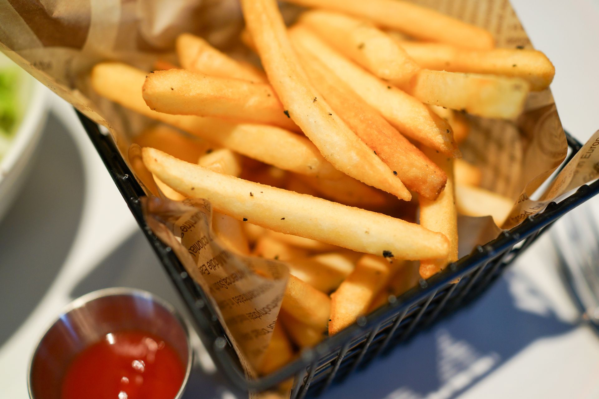 Fried chicken and salad in takeout containers on a white surface, with dipping sauces.