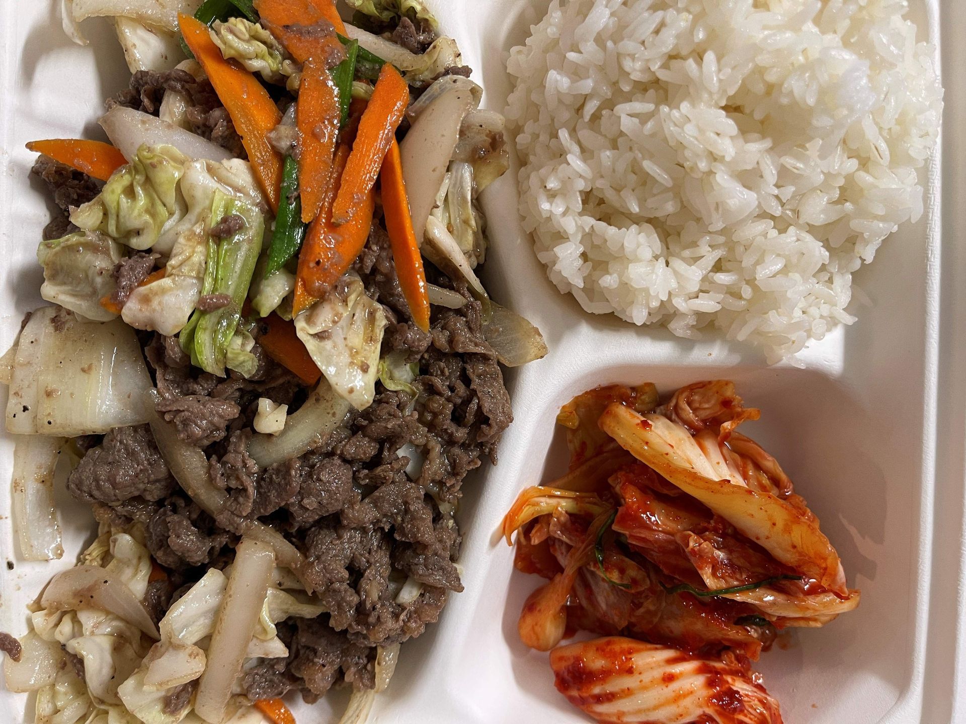Chicken salad with dressing on a bed of lettuce and shredded vegetables, served in a silver tray.