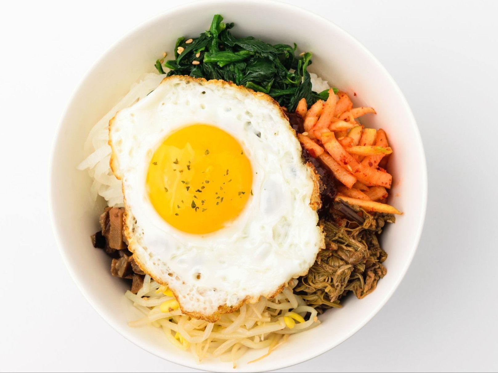 Chicken salad with greens and shredded vegetables drizzled with sauce on a silver tray.