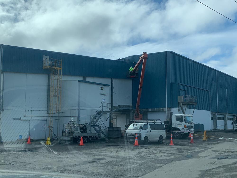 A man is painting the side of a building with a crane.