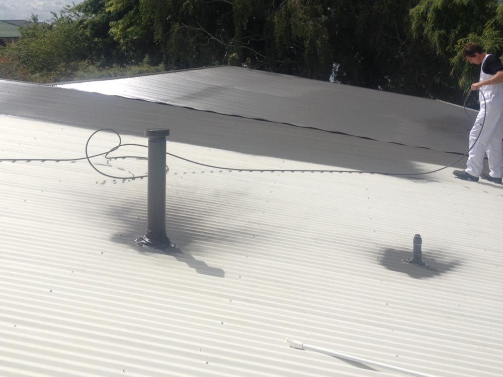 A man is standing on top of a white roof.