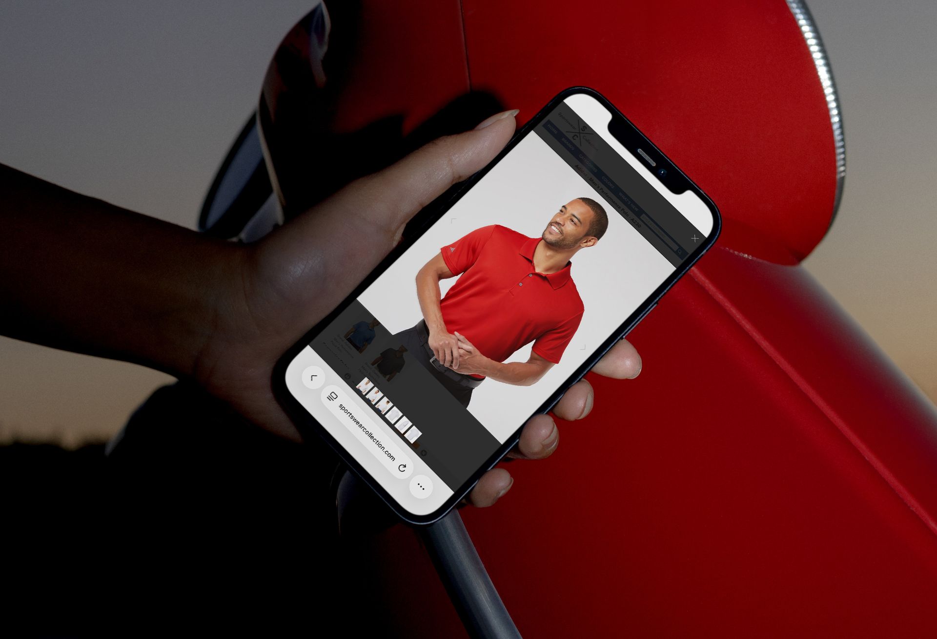 Person holding phone displaying website with photo of smiling man in red shirt.