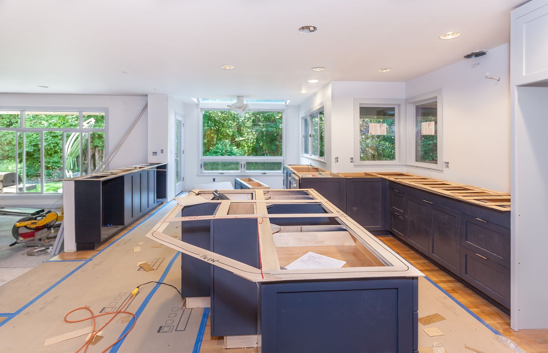 Kitchen under renovation with blue cabinets, unfinished island, and tools on the floor