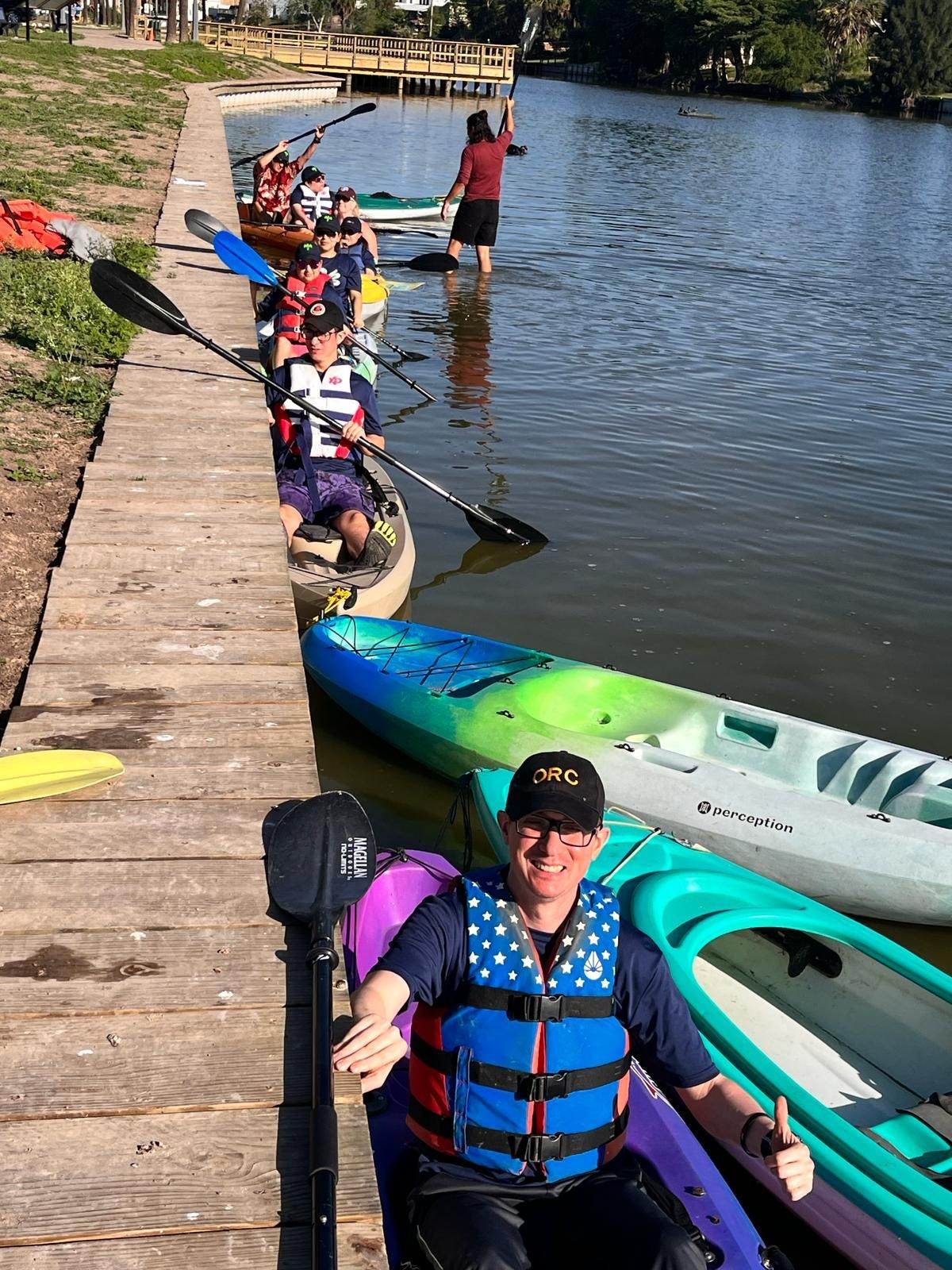 A man in a life jacket is sitting in a kayak giving a thumbs up.