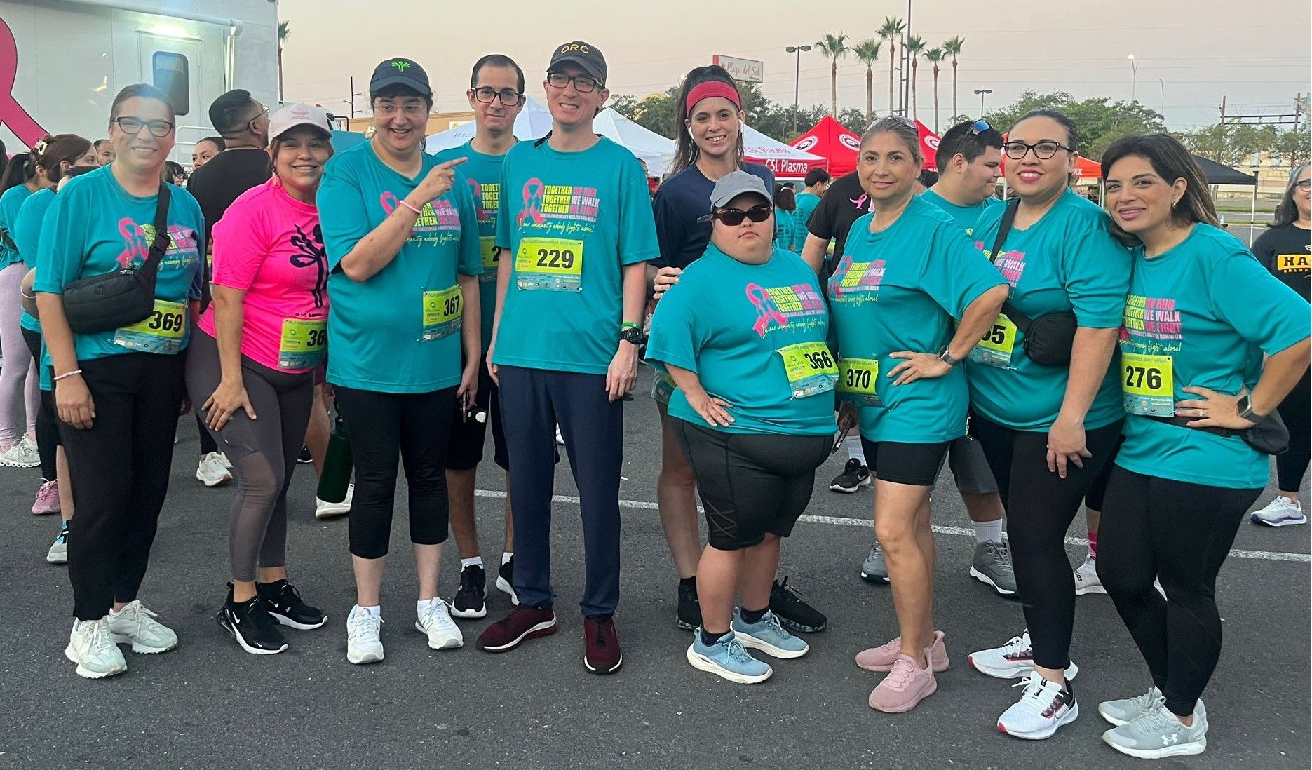 A group of people wearing teal shirts are posing for a picture.