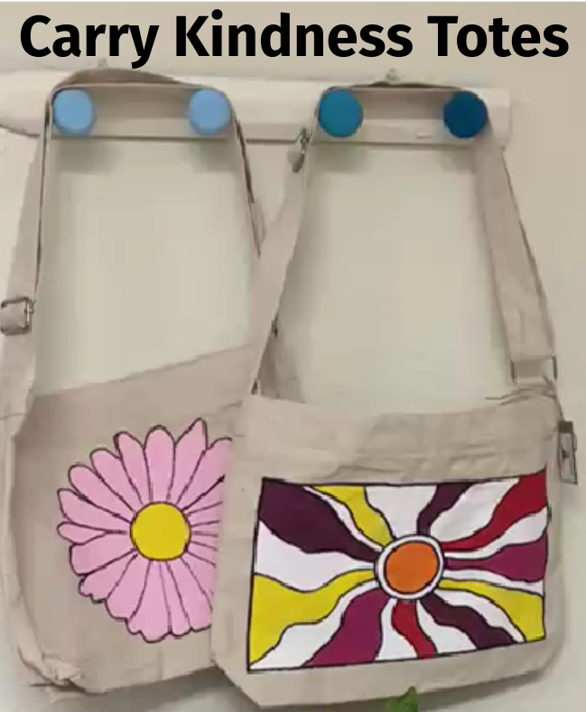 Two beige tote bags with painted floral designs hanging on wall.