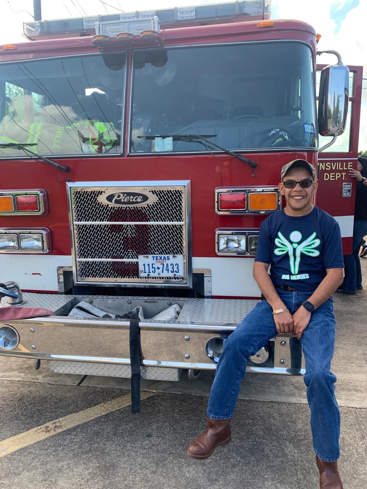 A man is sitting on the front of a fire truck.