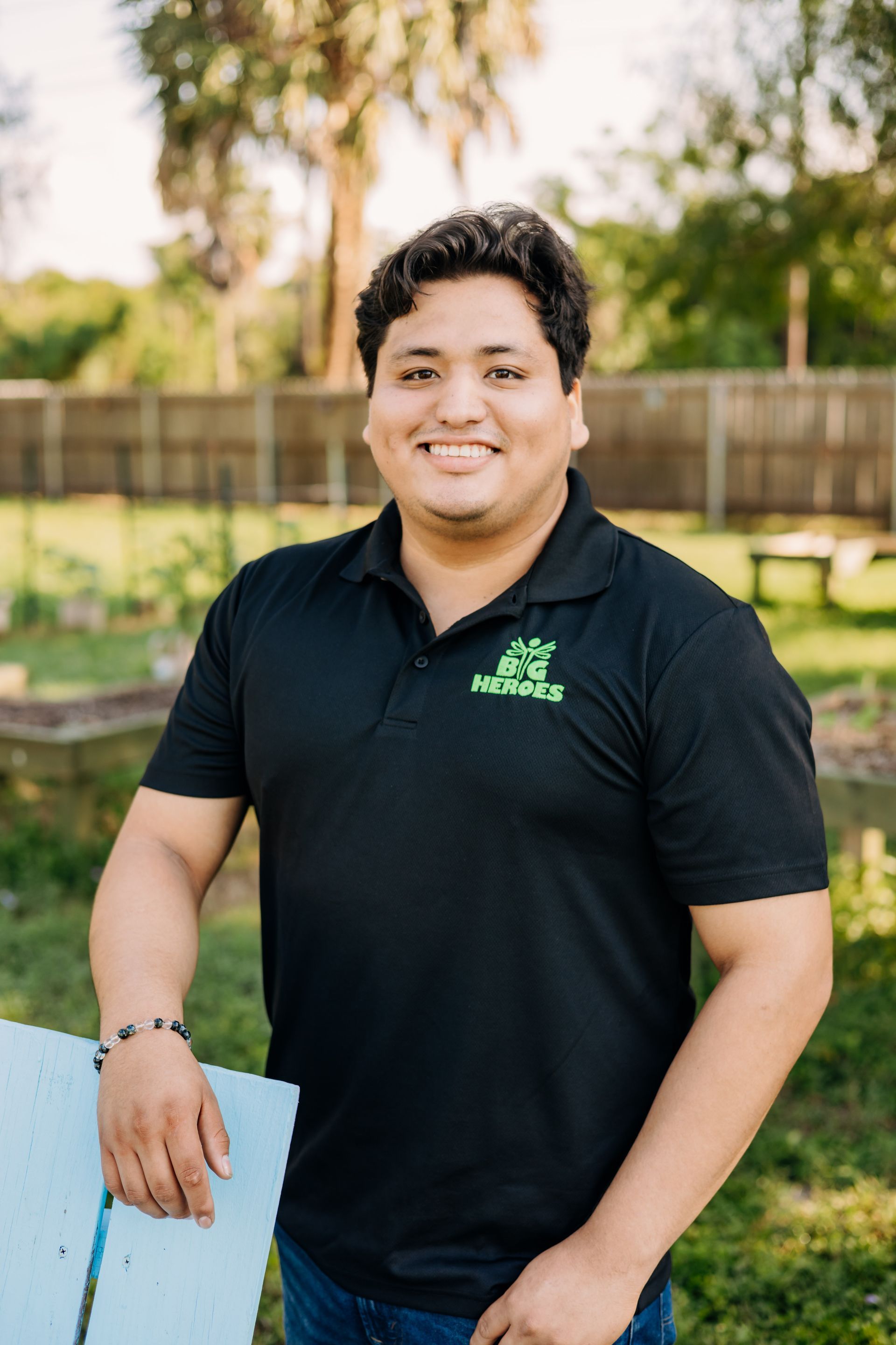 A man in a black shirt is standing in the grass holding a piece of paper.