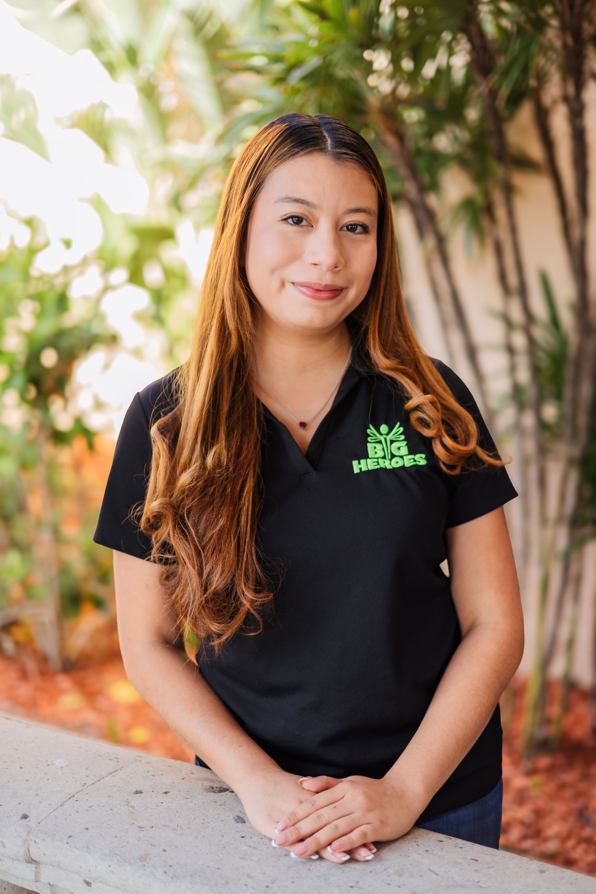 A man in a blue shirt is standing in front of a wooden picnic table.