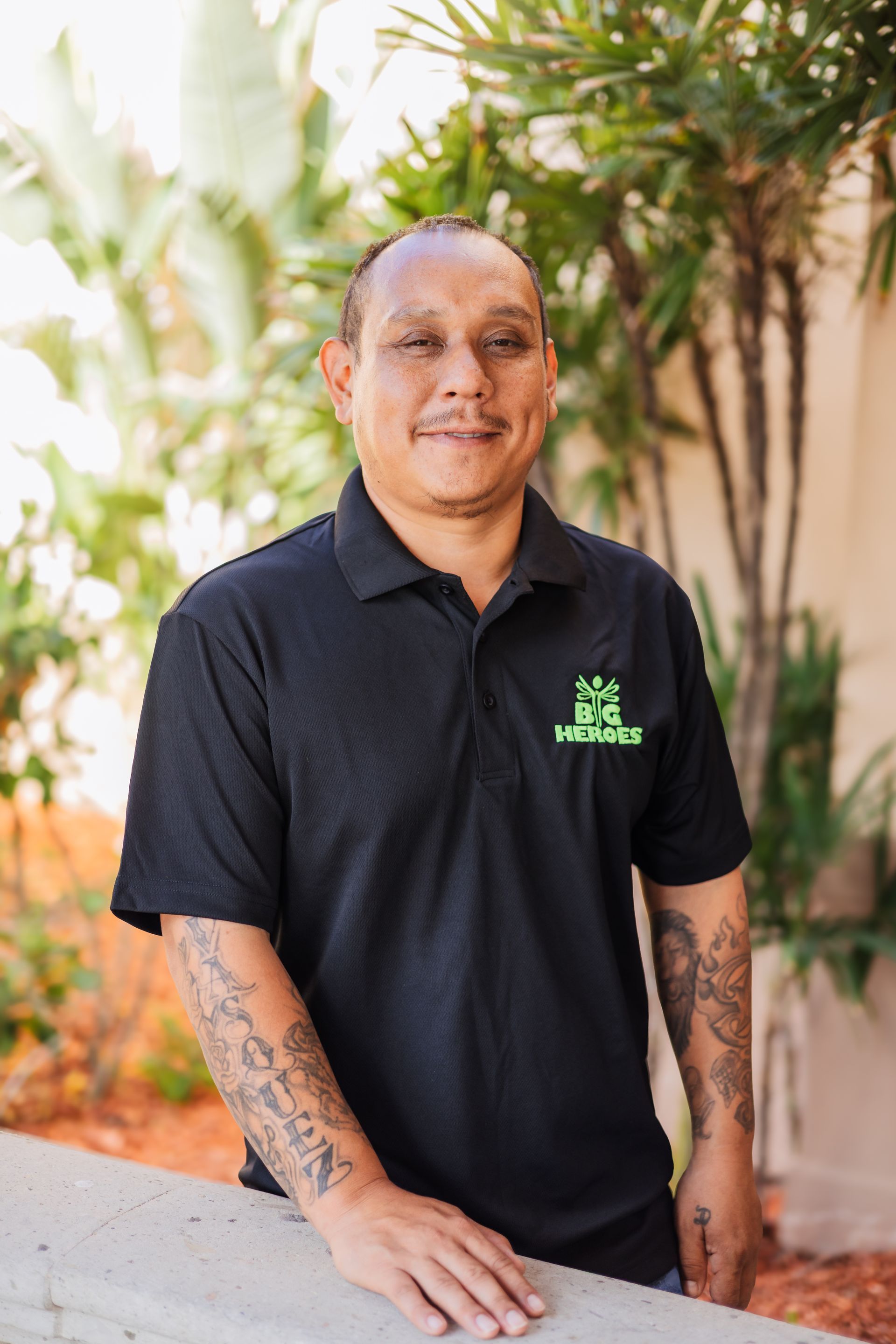 A woman wearing glasses and a black shirt is standing next to a blue bench.