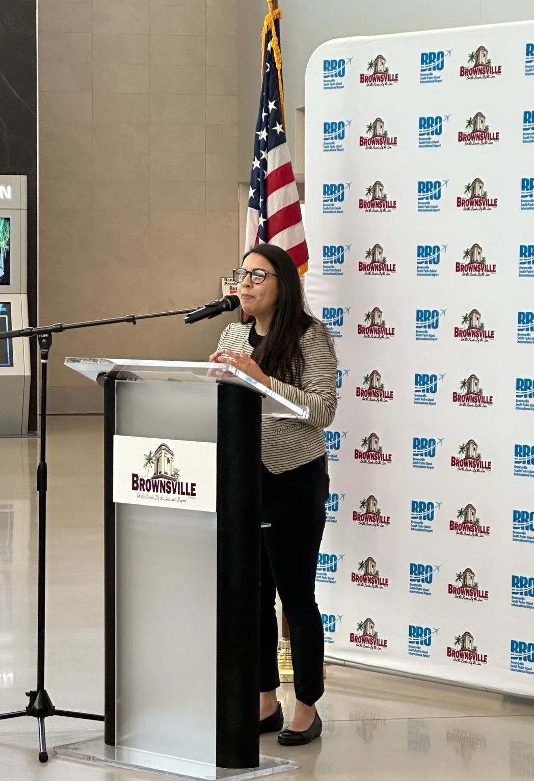 A woman is standing at a podium speaking into a microphone.