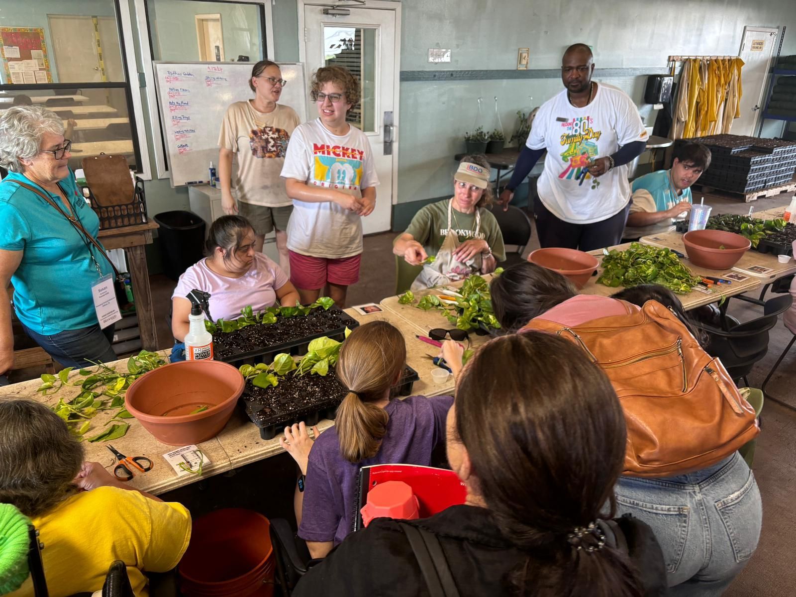 A group of people are sitting around a table with potted plants.