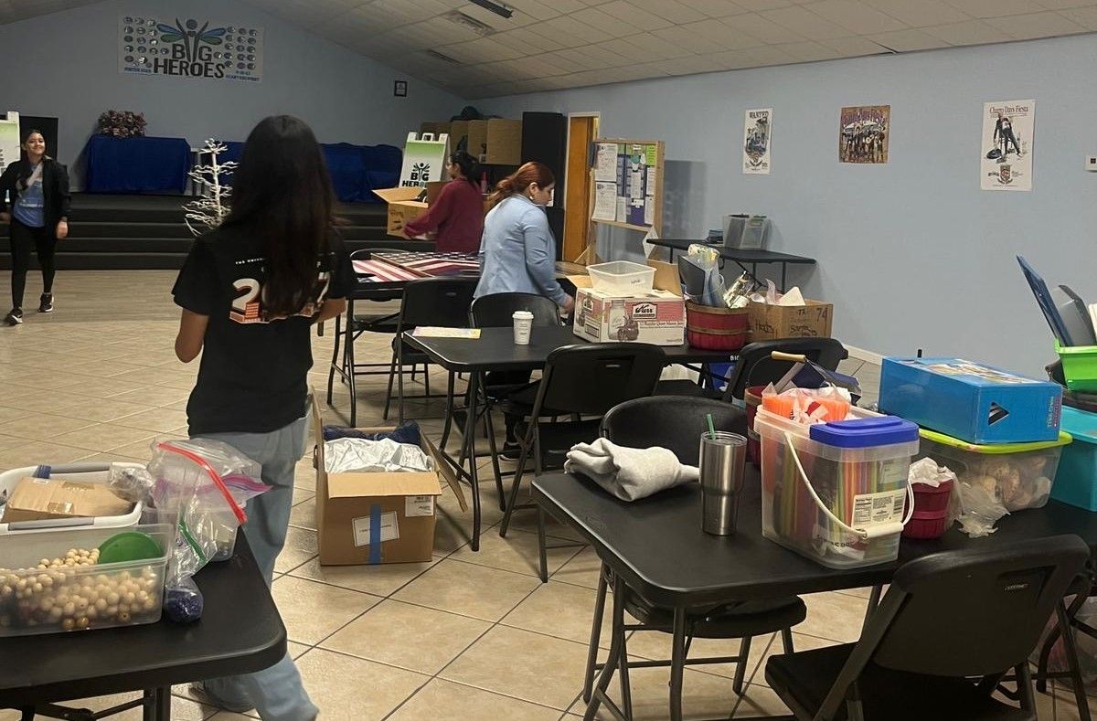A woman is standing in a room filled with tables and chairs