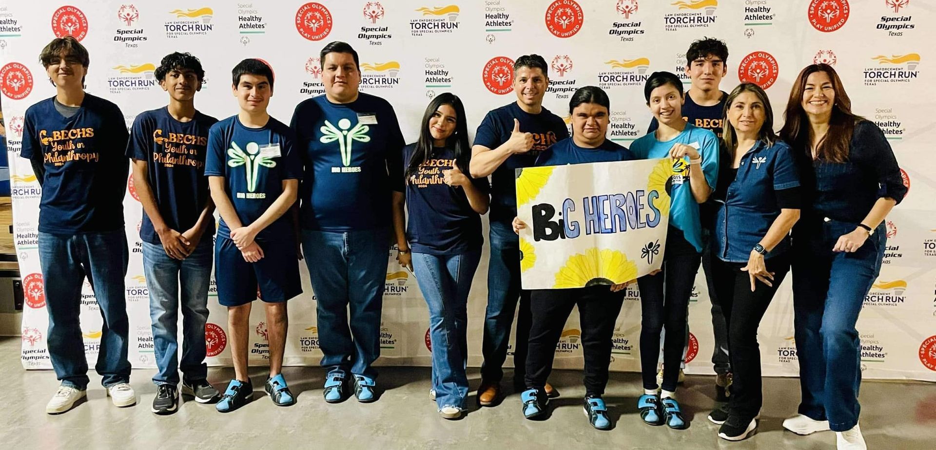 A group of people standing next to each other in front of a wall holding a sign.