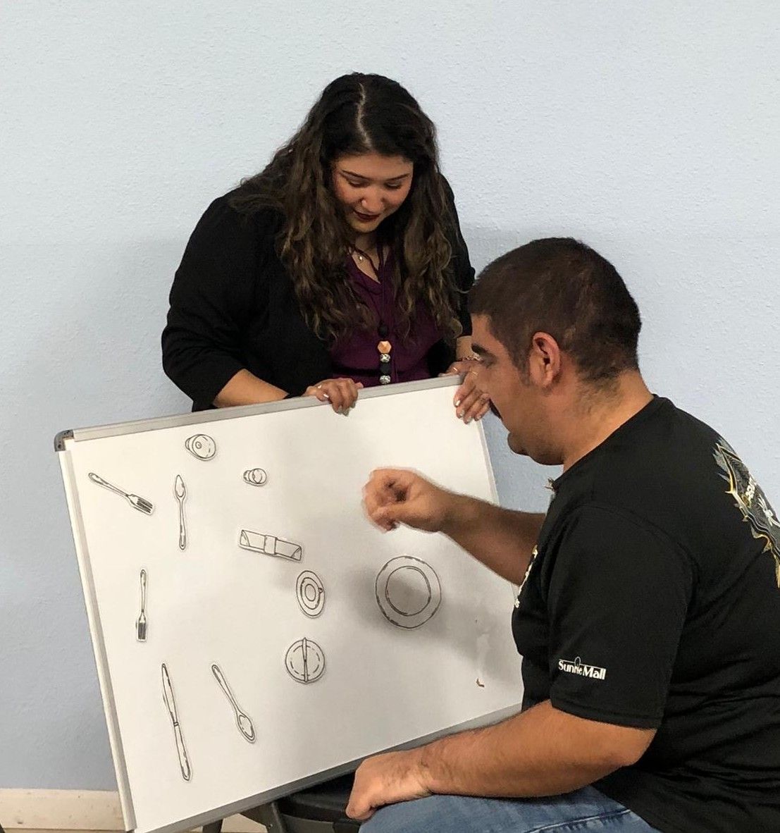 A man and a woman are looking at a white board