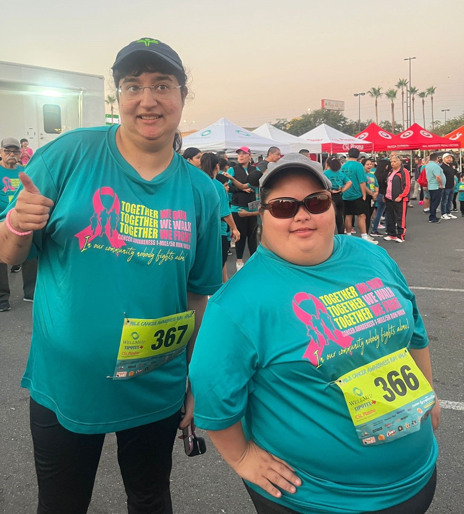 Two women are standing next to each other in a parking lot.