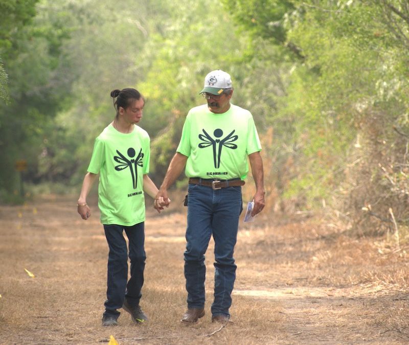 A man and a woman are walking down a dirt path holding hands