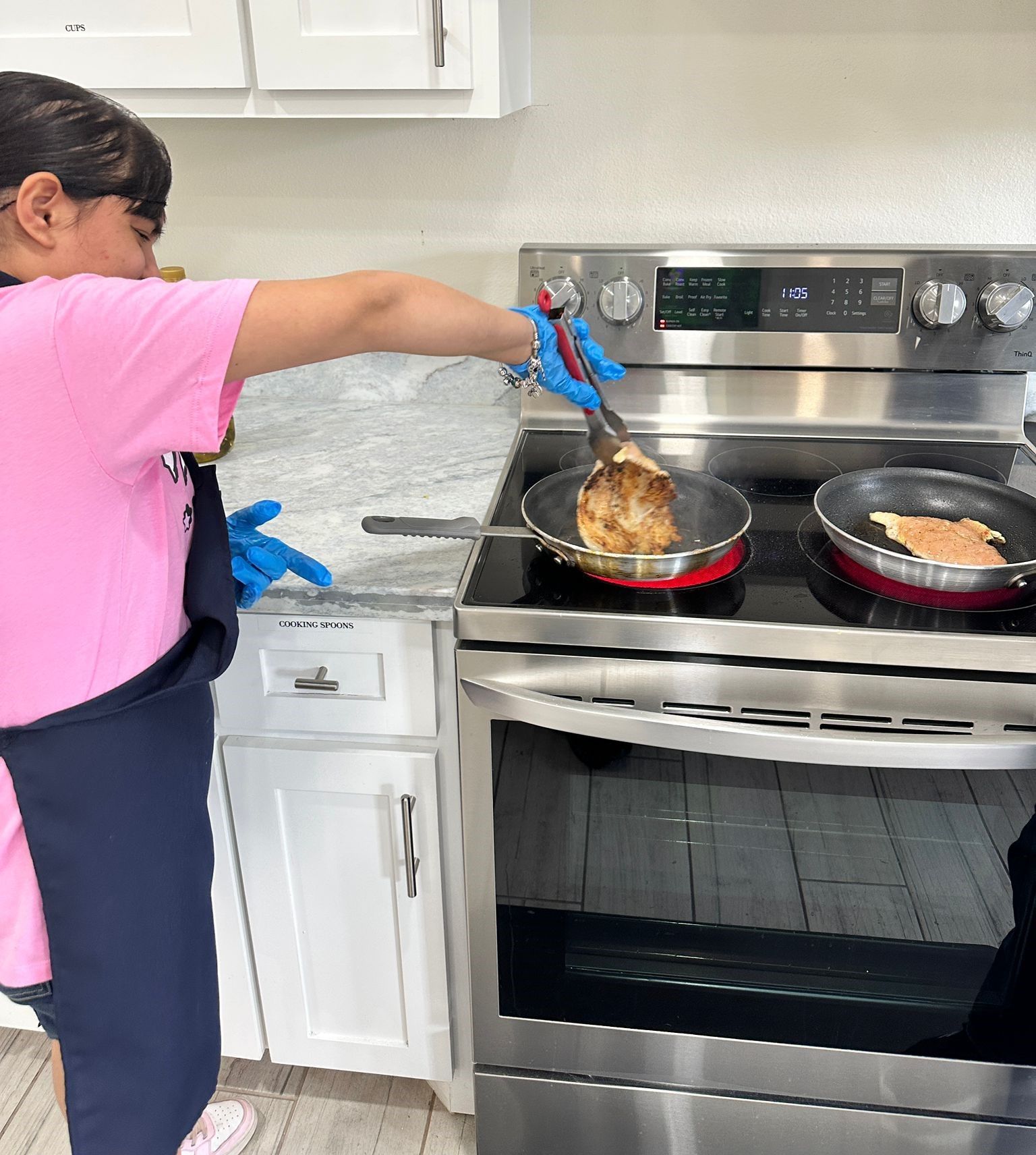 A young girl is cooking food on a stove in a kitchen.