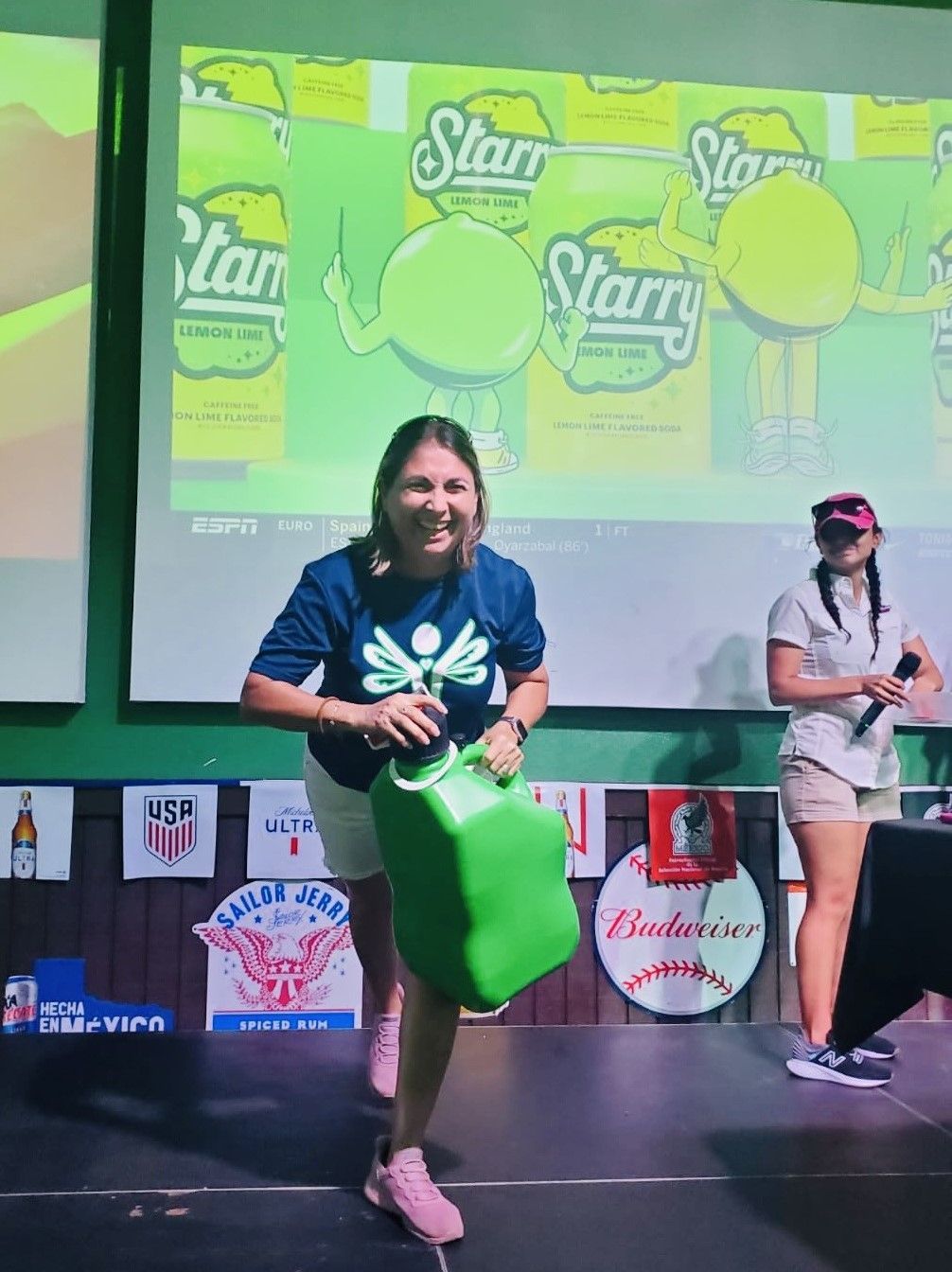 A woman is holding a green barrel on a stage.