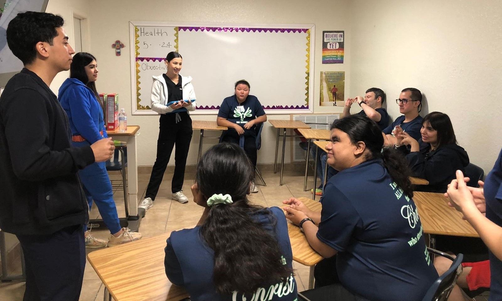 A group of people are sitting at desks in a classroom.