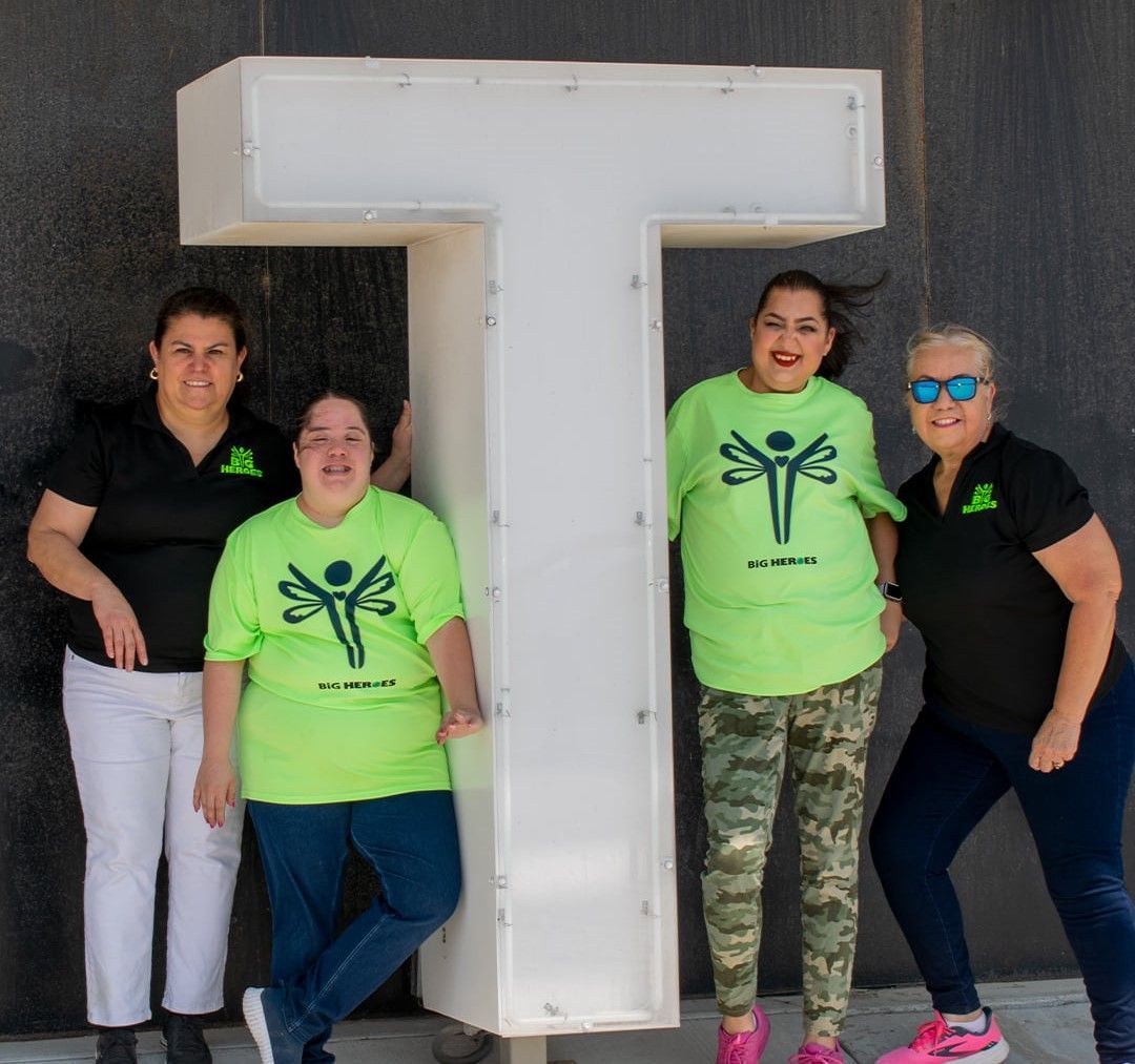 A group of women standing in front of a large letter t