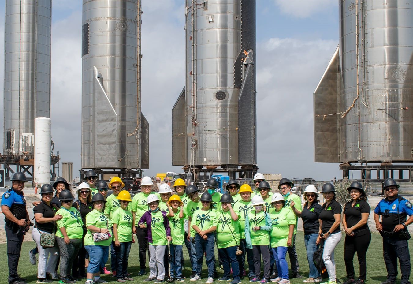 A group of people are posing for a picture in front of rockets.