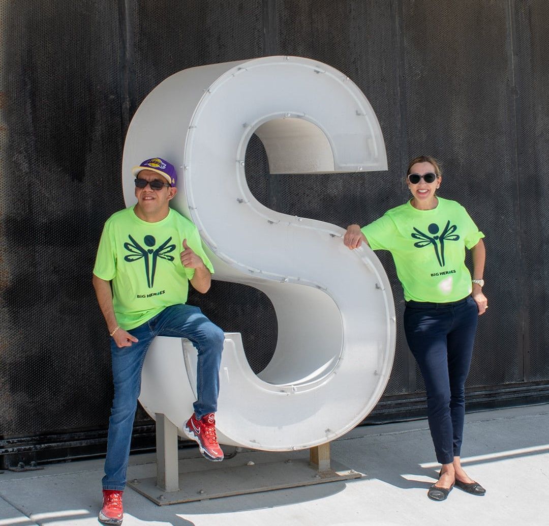 A man and a woman standing next to a large letter s