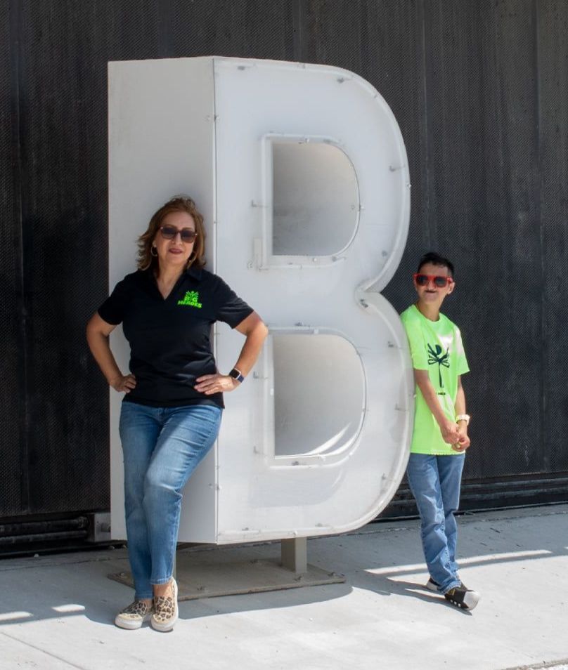 A woman and a boy standing next to a large letter b