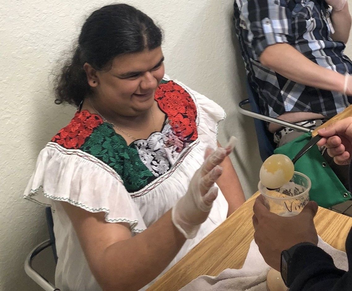 A woman in a white dress is sitting at a table