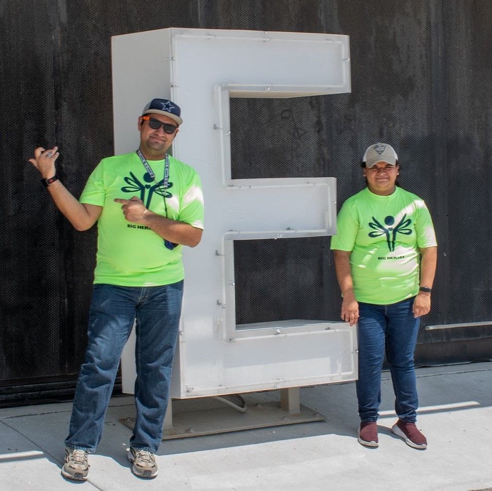 Two people standing in front of a large letter e