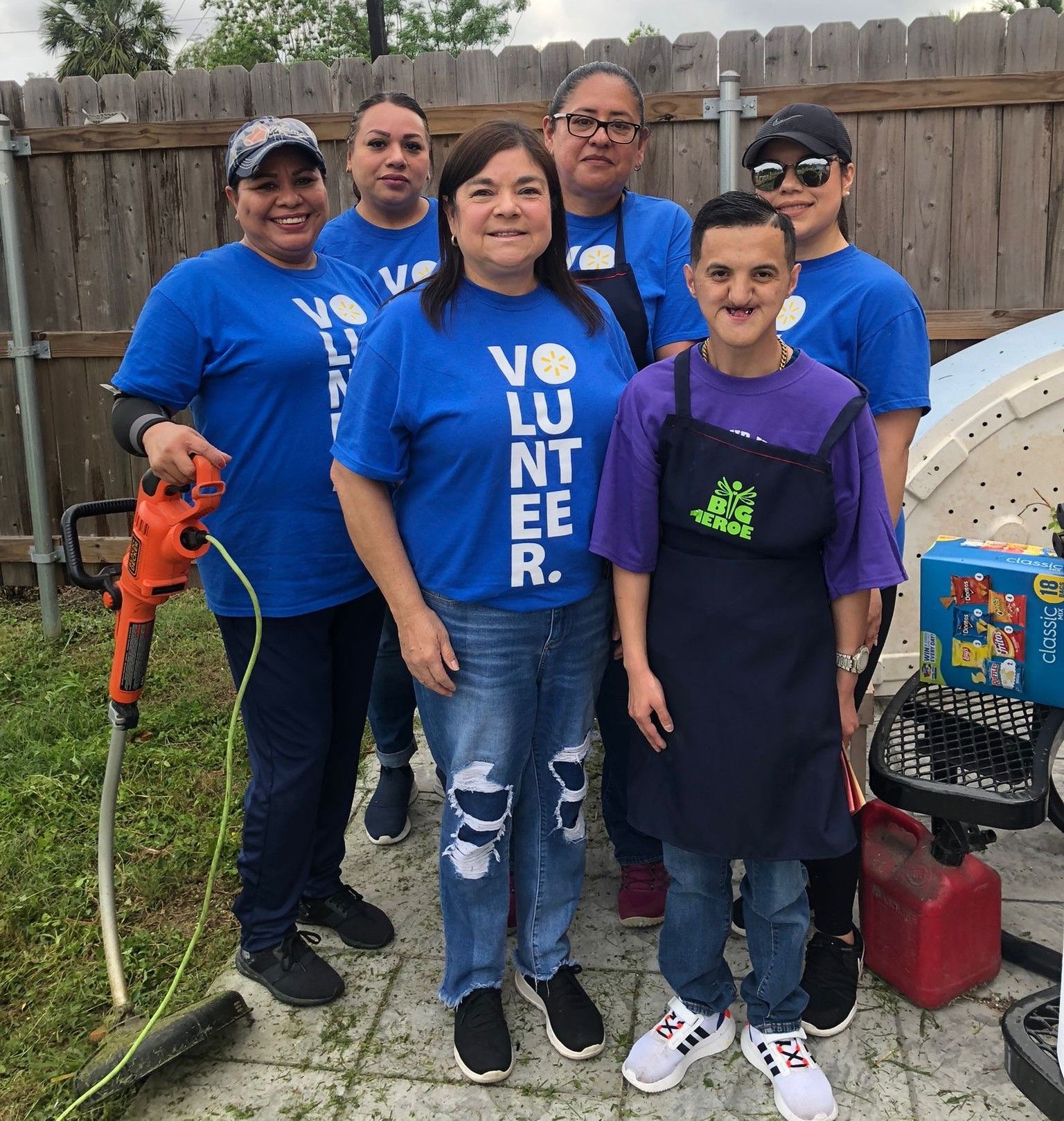 A group of people wearing blue shirts that say volunteer are posing for a picture