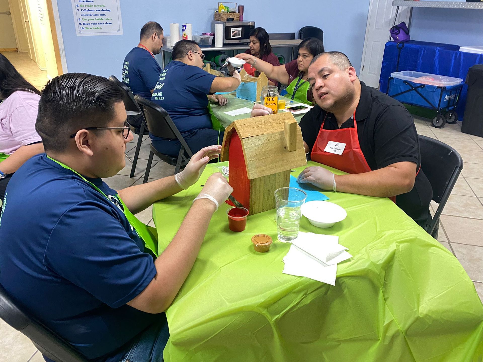 A group of people are sitting at a table with a green table cloth.
