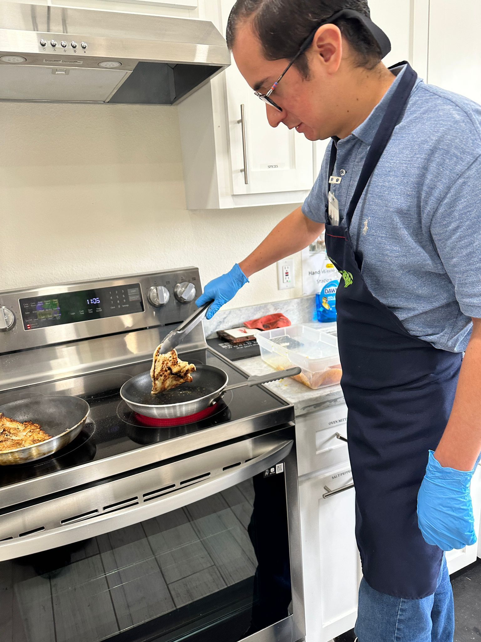 A man is cooking food on a stove in a kitchen.