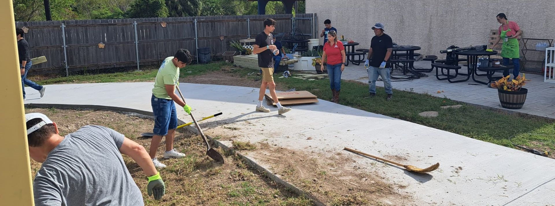 A group of people are working on a sidewalk in a yard.